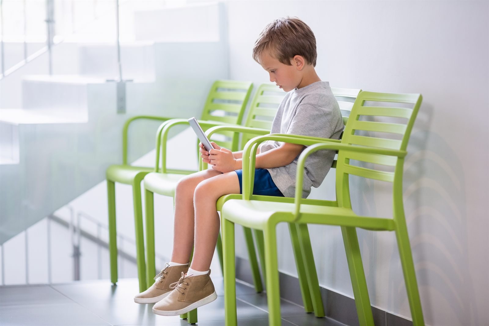 Copil relaxat cu o tabletă în sala de așteptare a clinicii | GetVizual