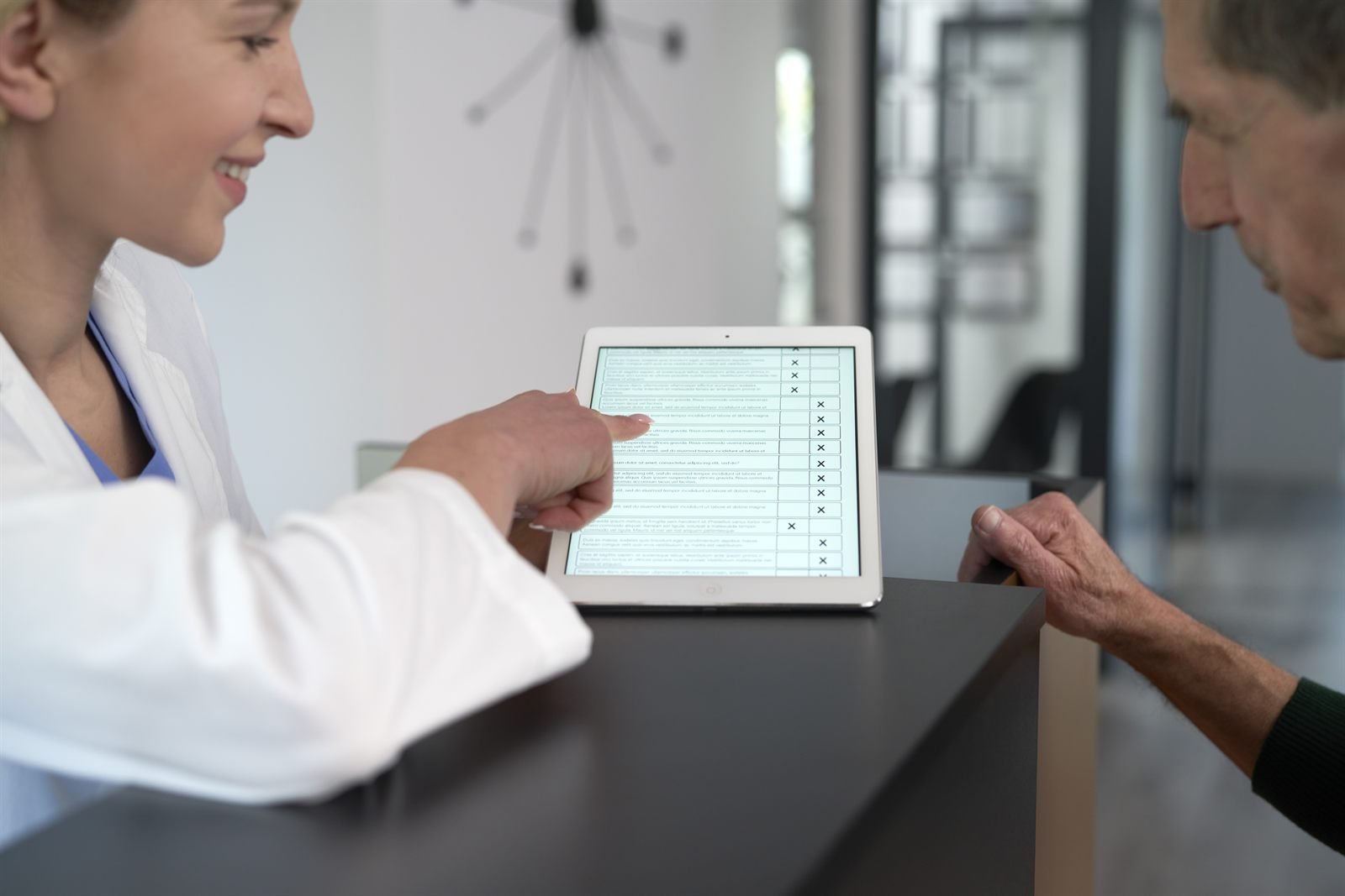 Medic discutând cu un pacient feedback-ul pe o tabletă în clinică | GetVizual