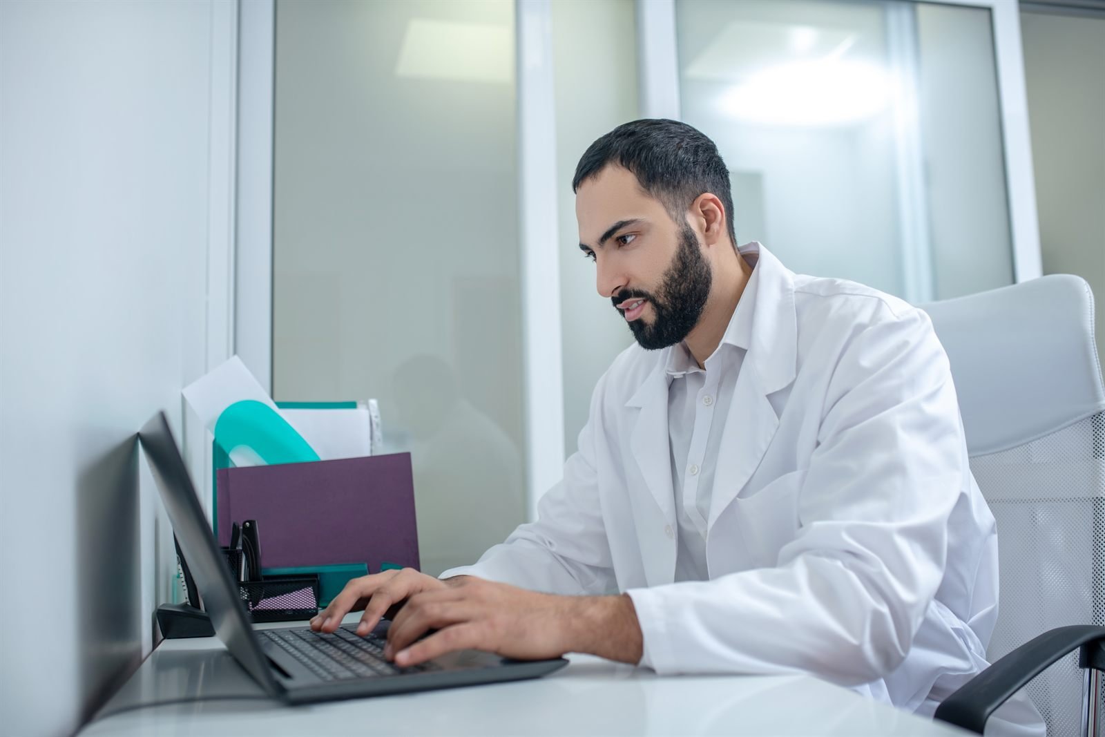 Medic în halat alb monitorizând recenziile online pe laptop | GetVizual