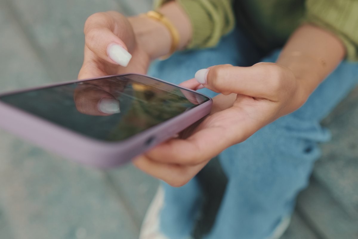 Femeie care ține telefonul în mână, văzută de aproape | GetVizual