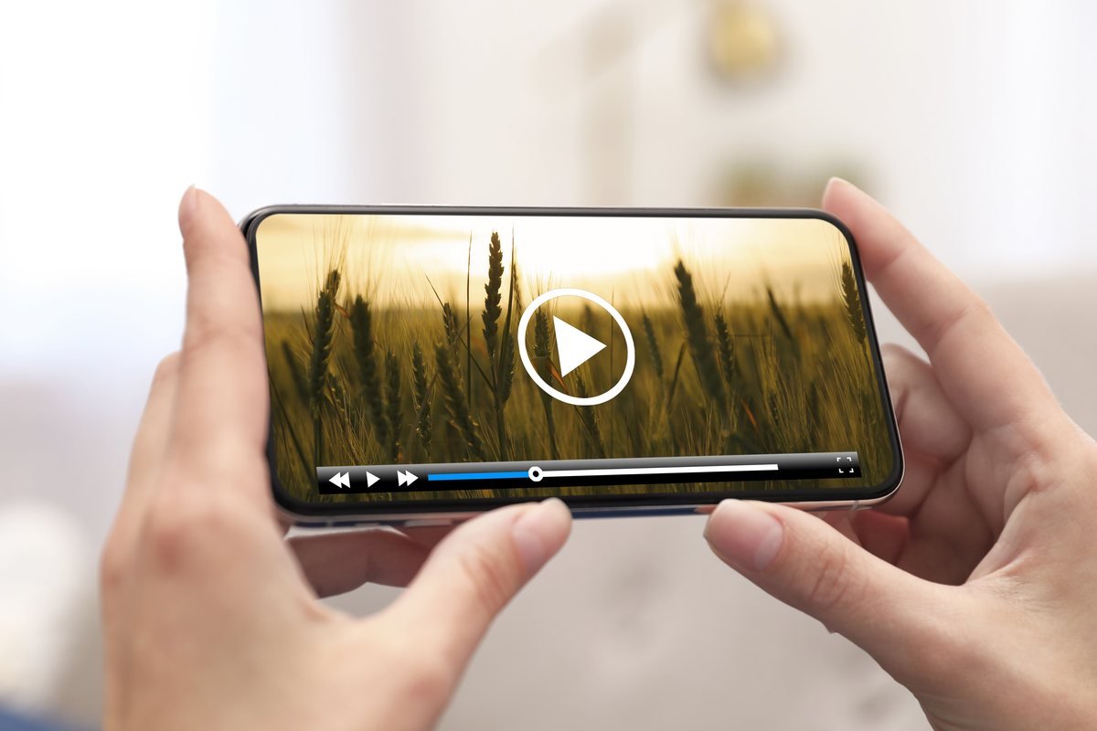 Mâini care țin un telefon pe care rulează un videoclip | GetVizual